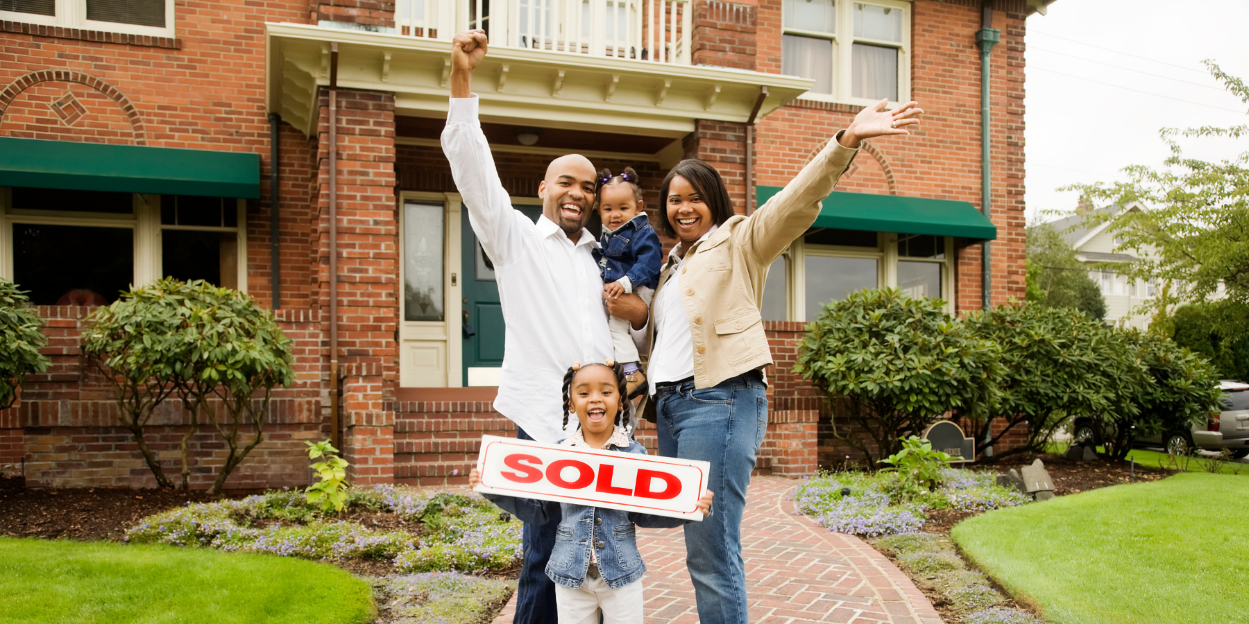 Family in front of a home with a sold sign