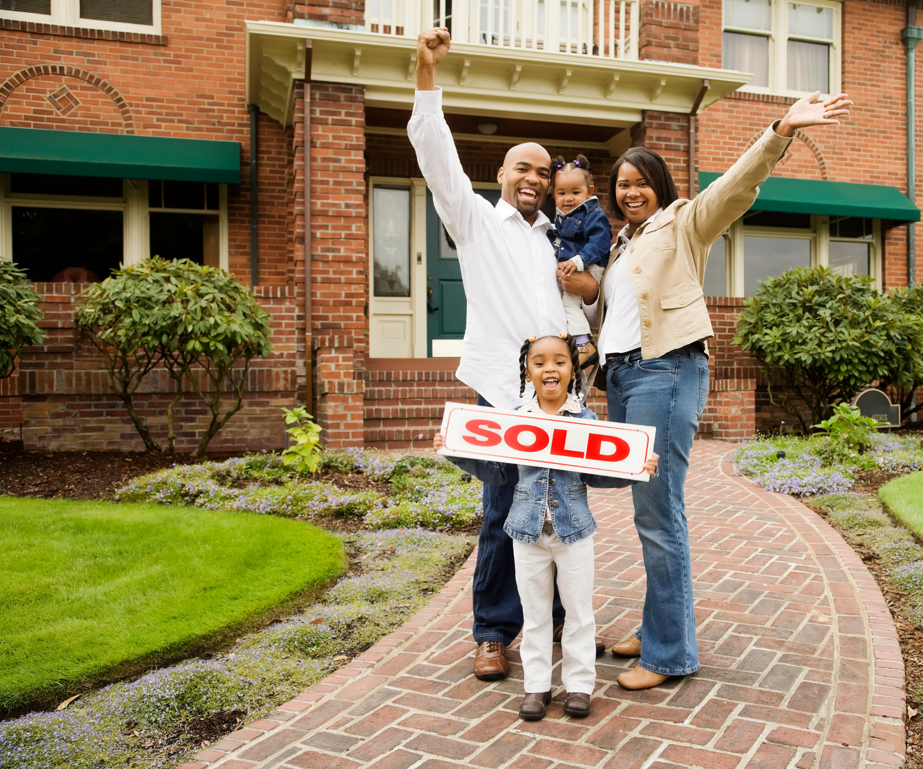 Family in front of a home with a sold sign